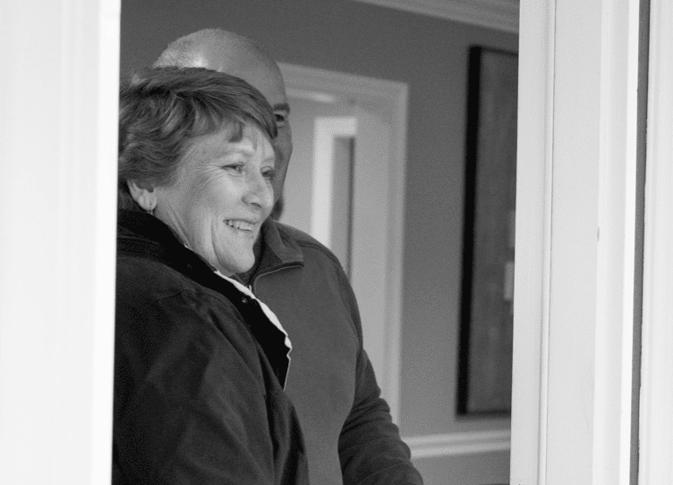 Marilyn, a caregiver to her husband with Pseudobulbar Affect (PBA) walking through a door
